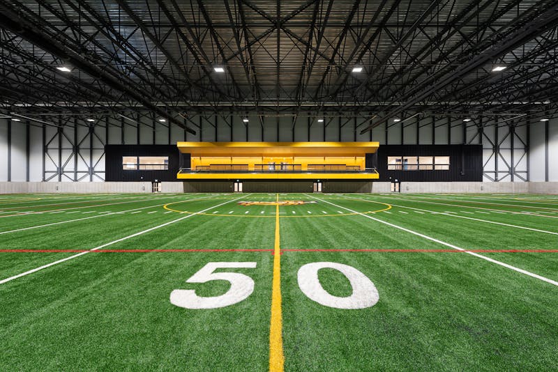 Vue à un point de fuite de l'estrade jaune dans un centre sportif intérieur. La surface de jeux est au premier plan.