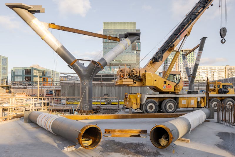 Perspective architecturale sur un chantier de construction ou paraisse des structures en acier et un équipement de levage.