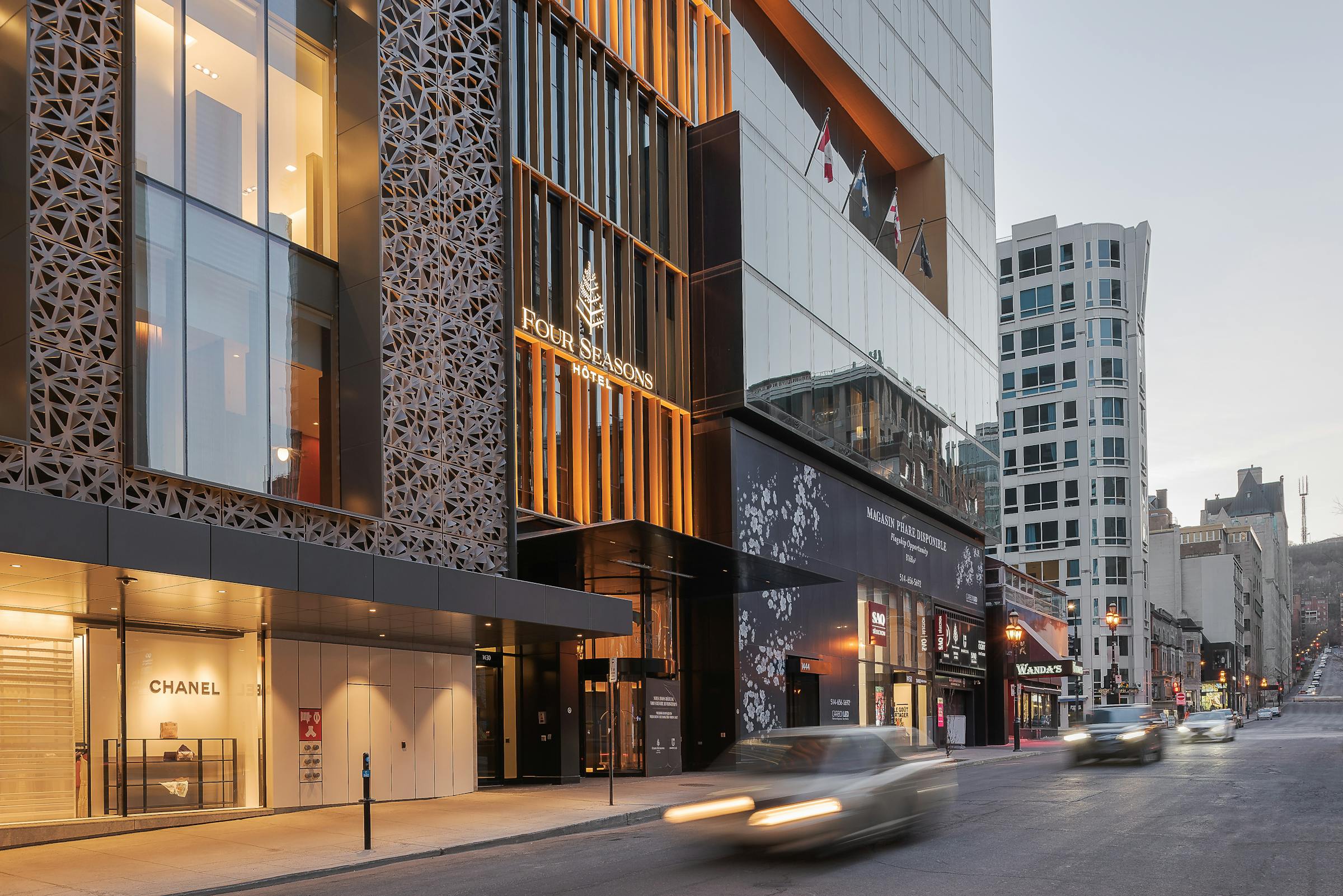 Photographie en lifestyle avec des voitures filant devant la facade architecturale d'un hôtel moderne.
