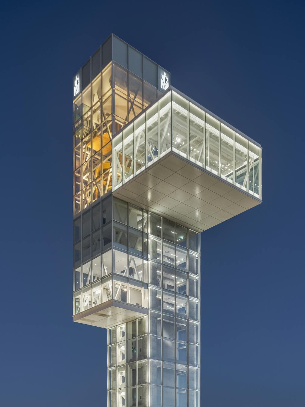 Photographie de nuit de la salle d'observation en porte-à-faux prise en contre-plongée. Ciel bleu nuit et éclairage artificiel dominant.