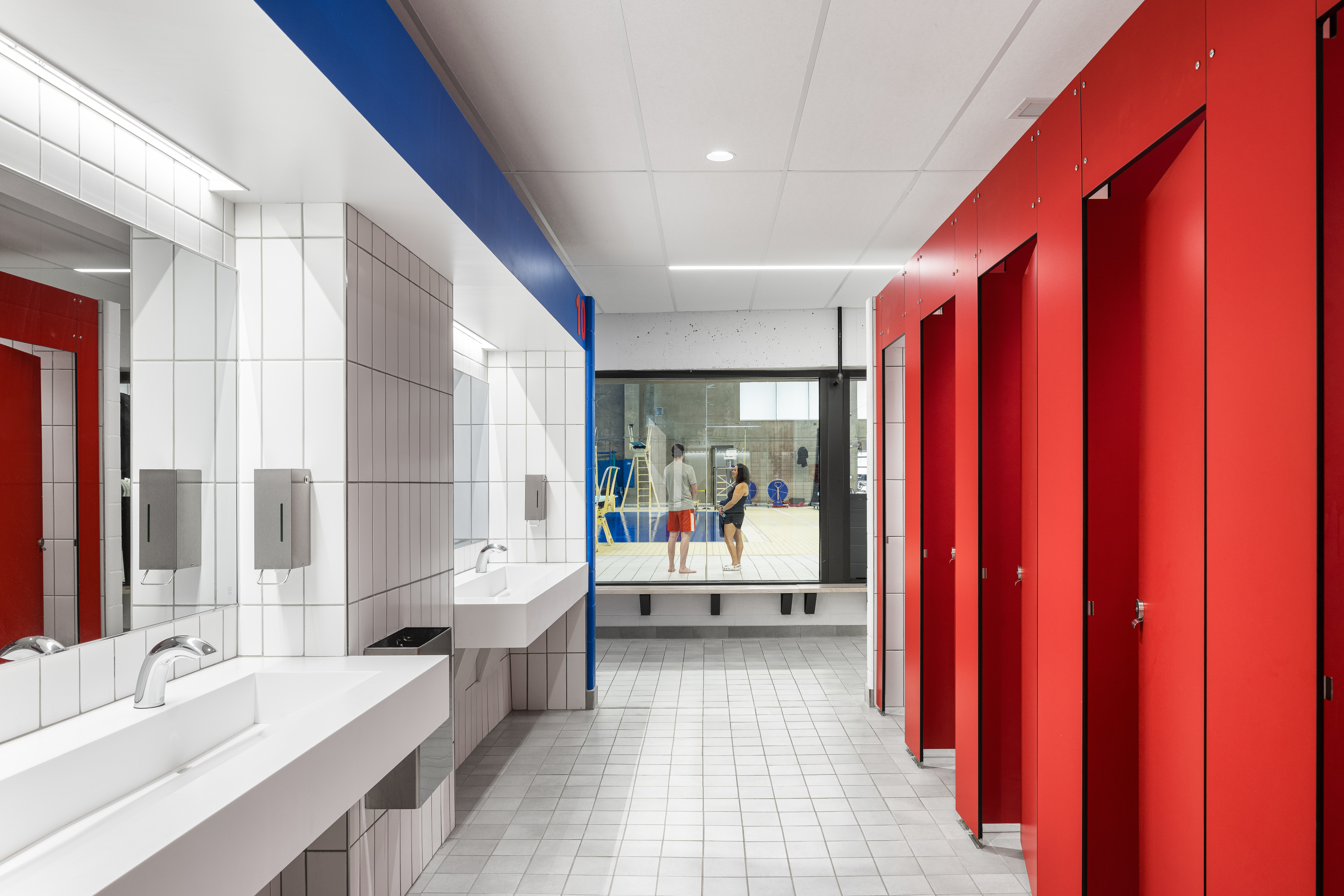Architectural photograph of a communal bathroom in shades of white and red, a universal changing room.