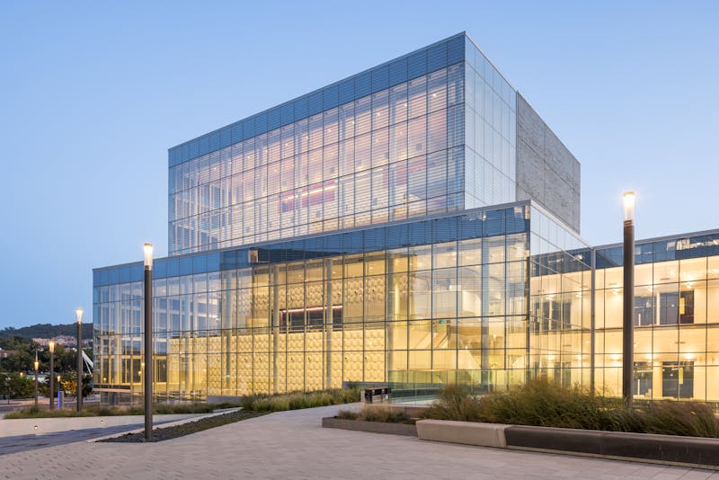 Photographie de nuit d'un bâtiment institutionnel vitré avec une forte dominance de l'éclairage intérieur.