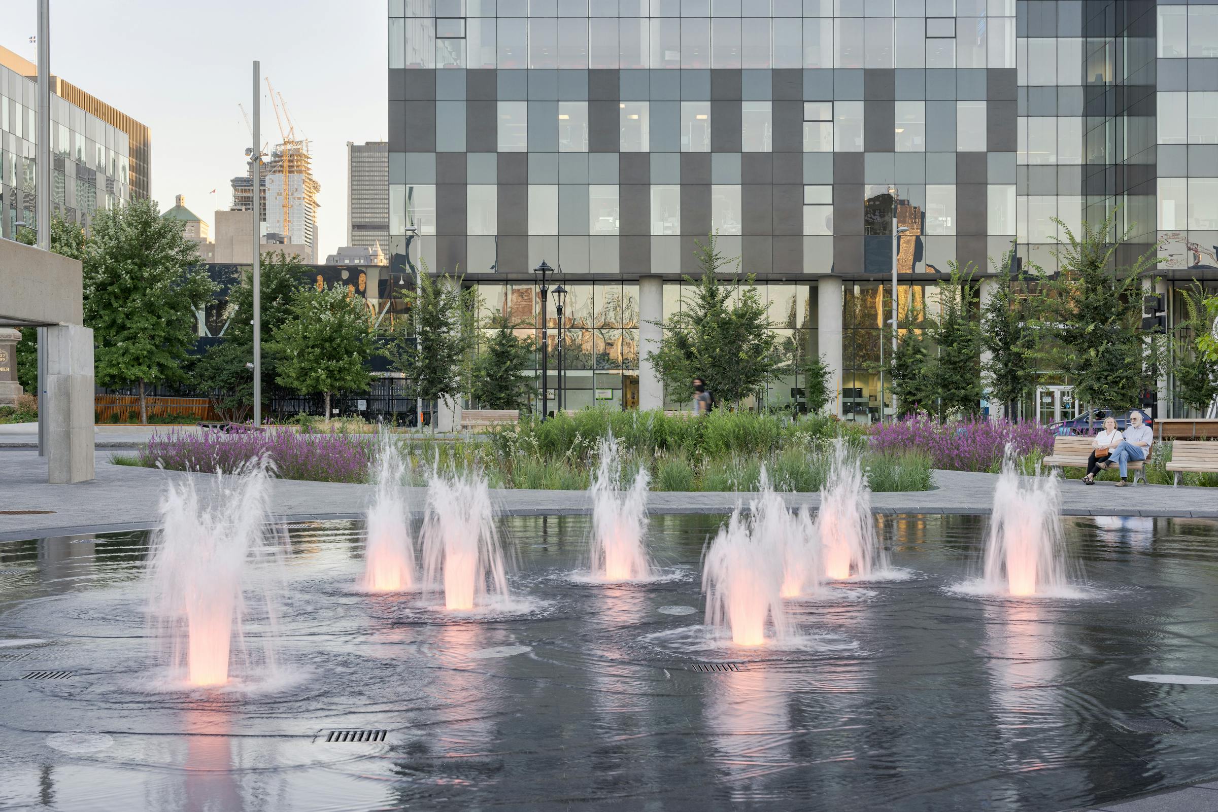 Fontaine et éclairage publique sur une place dans un environnement d'architecture urbaine.