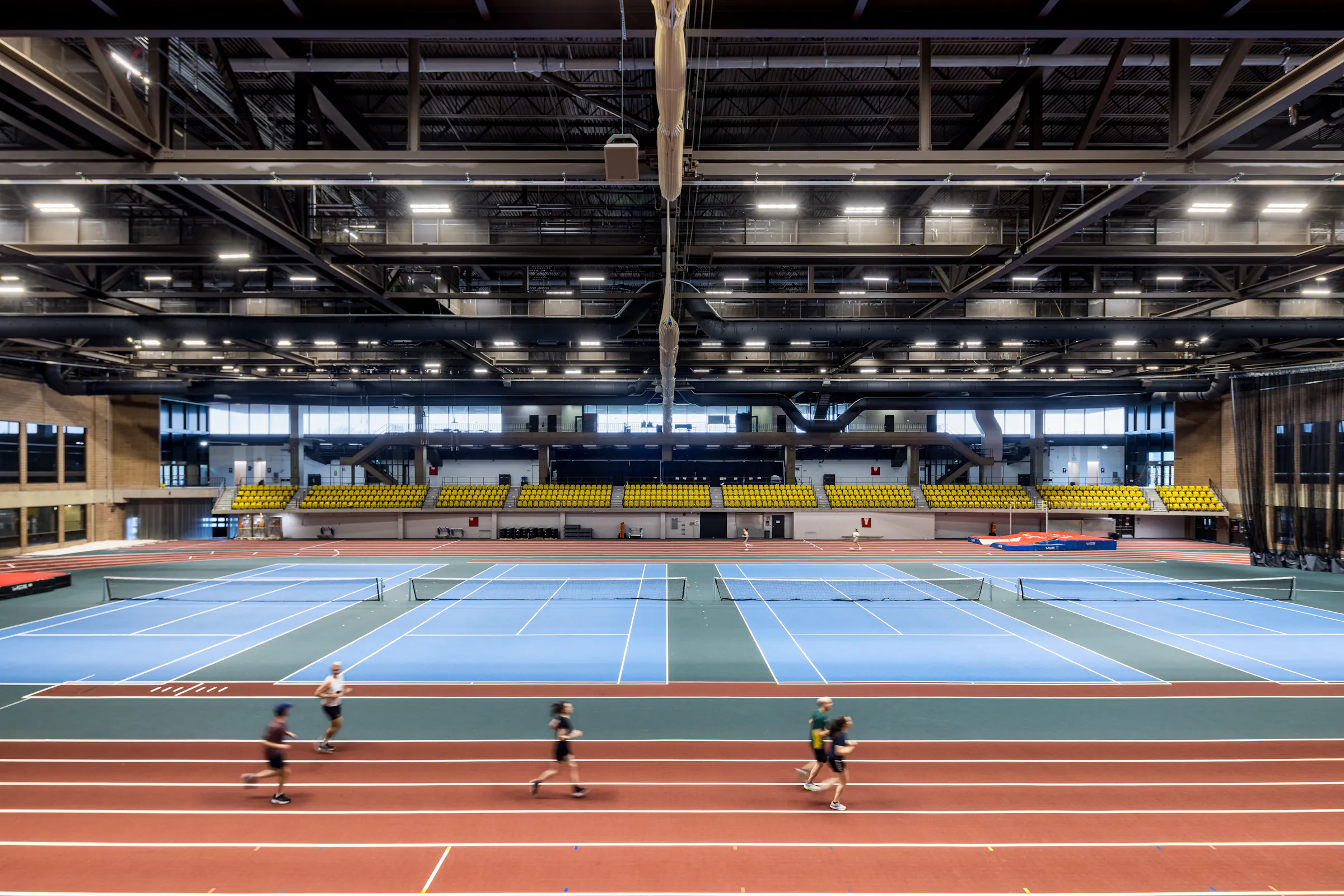 Architectural photograph of the indoor tennis courts and running track in the multi-sports hall.