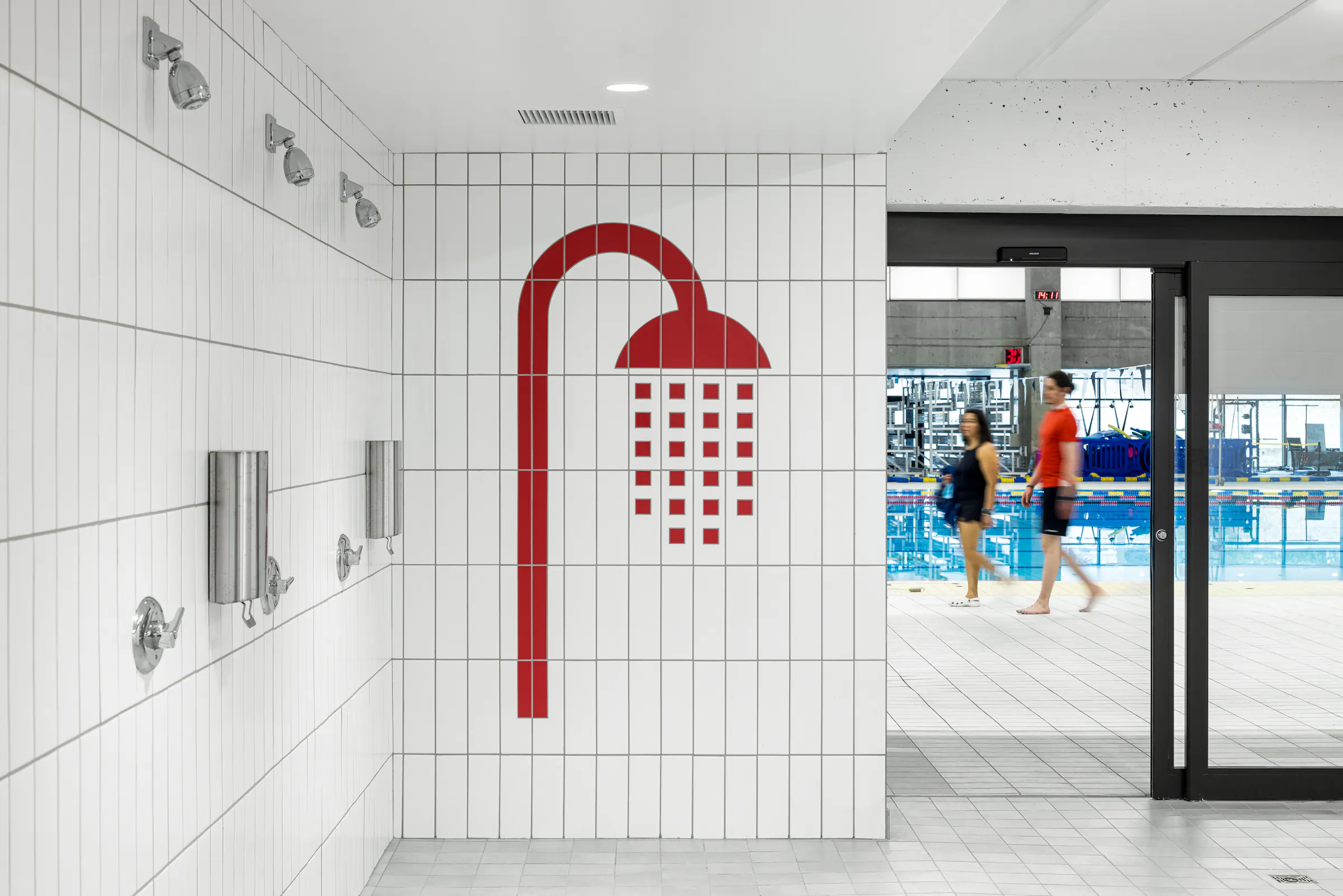 Architectural photograph of a bathroom, white tiled showers with red pictograms in a universal changing room.