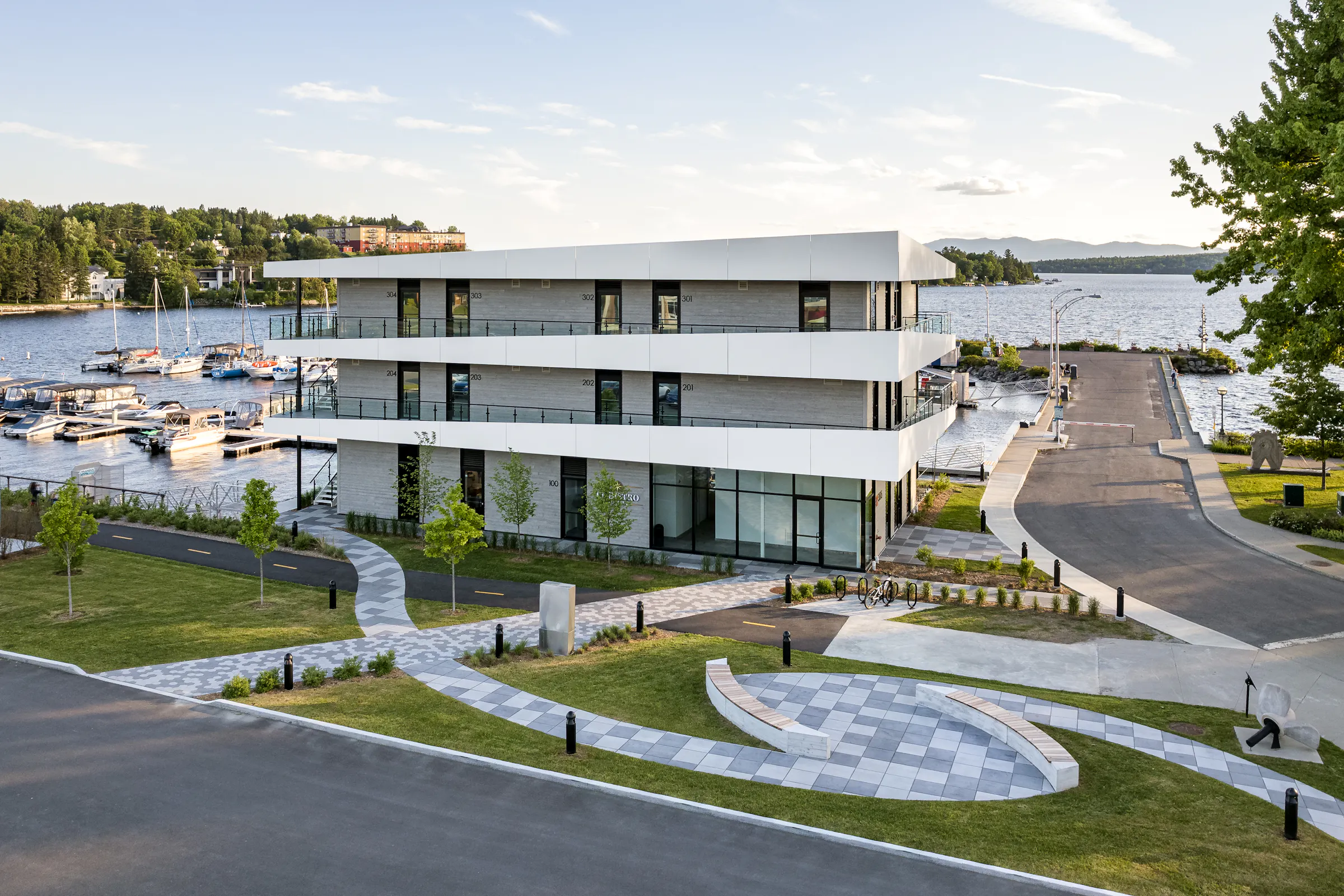 Photographie architecturale de La Capitainerie avec la marina et le lac en arrière-plan
