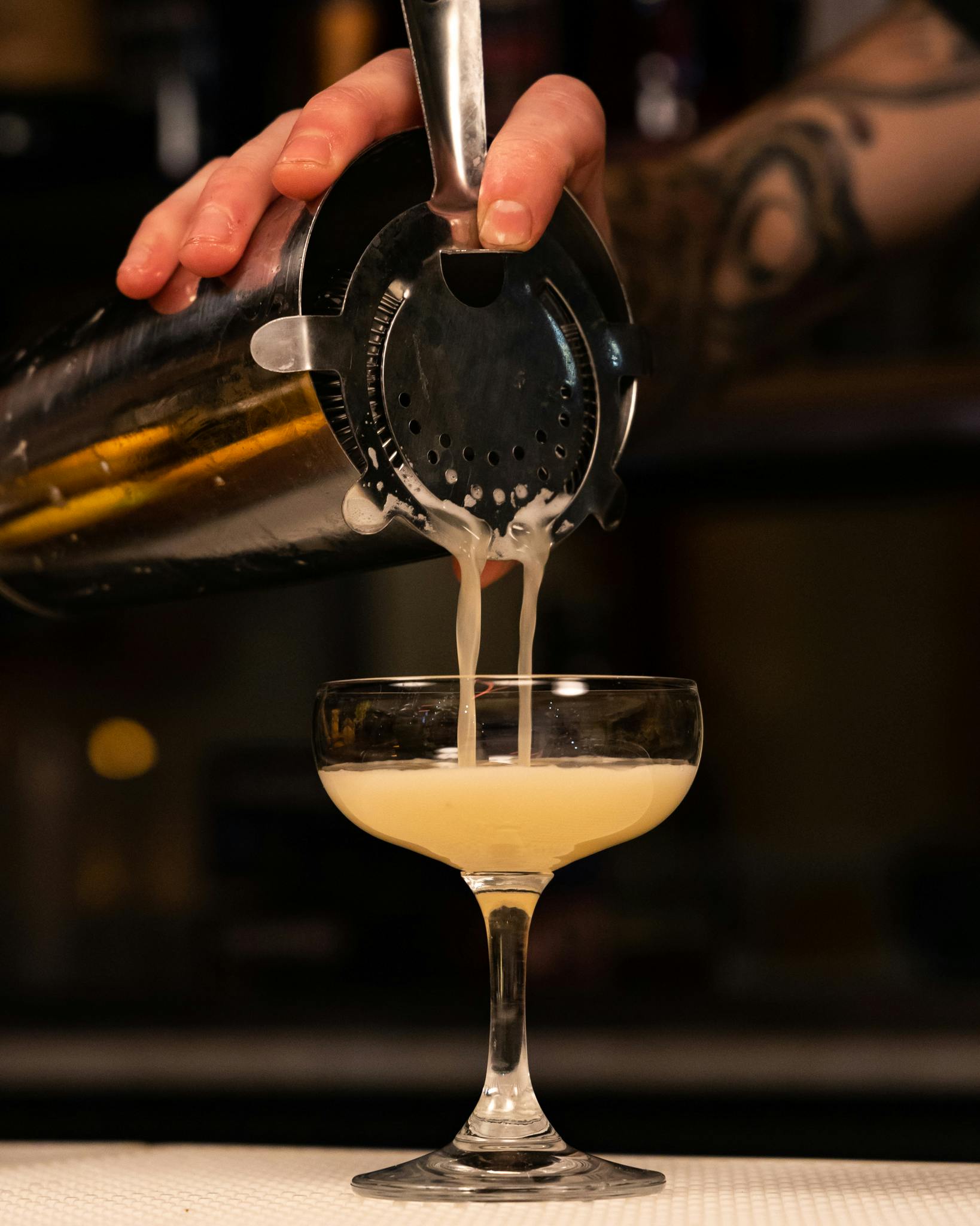 The Madagascar Sour being poured into a coupe glass