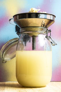 A photo of ginger juice in a jar with a funnel