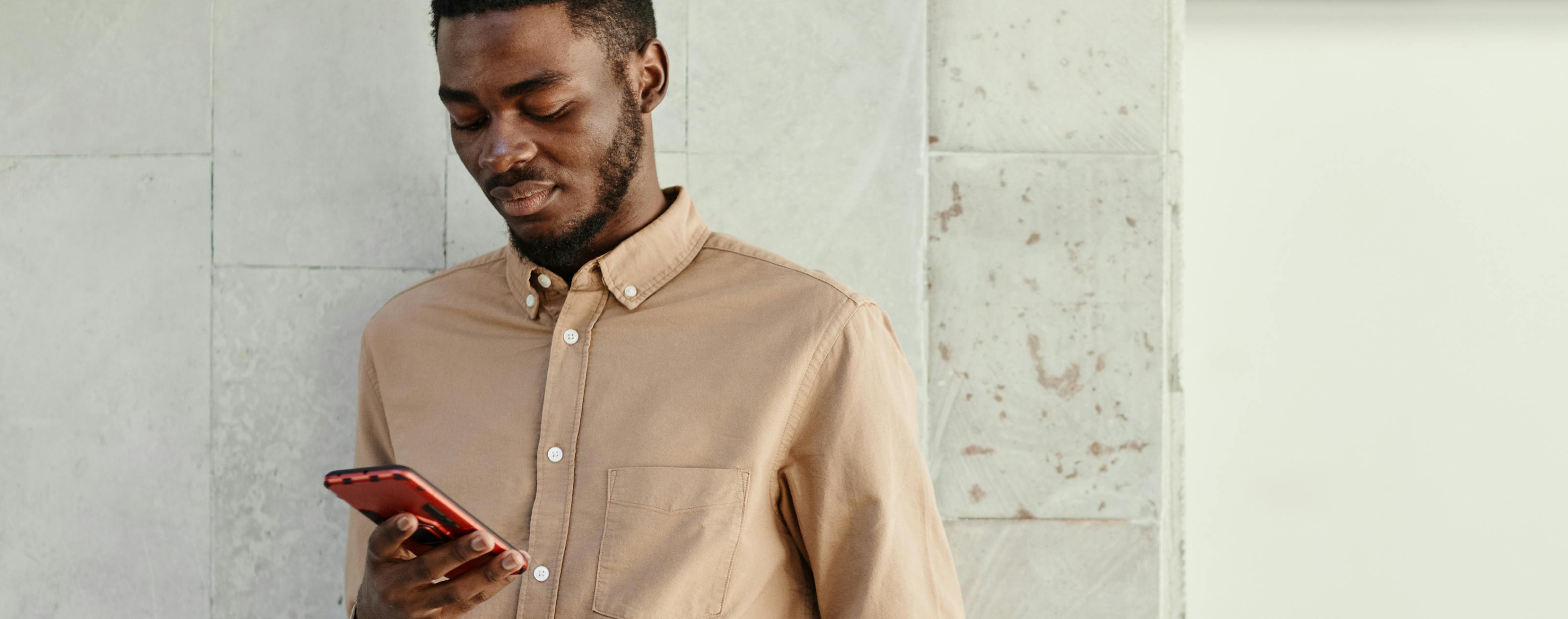 man in beige shirt looking at smart phone