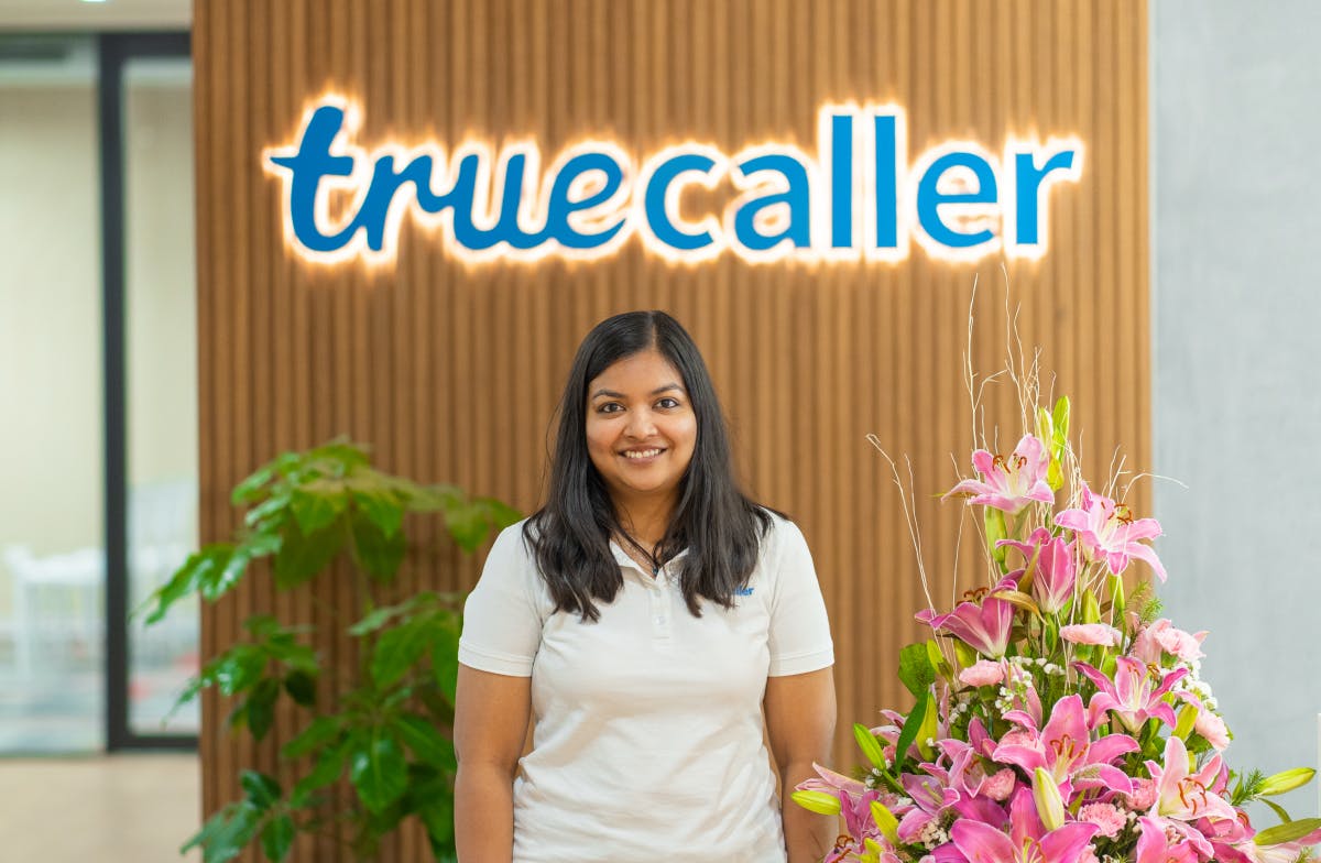 Rashmi Tondare, Backend Engineer, in front of the Truecaller logo in the Bangalore office.