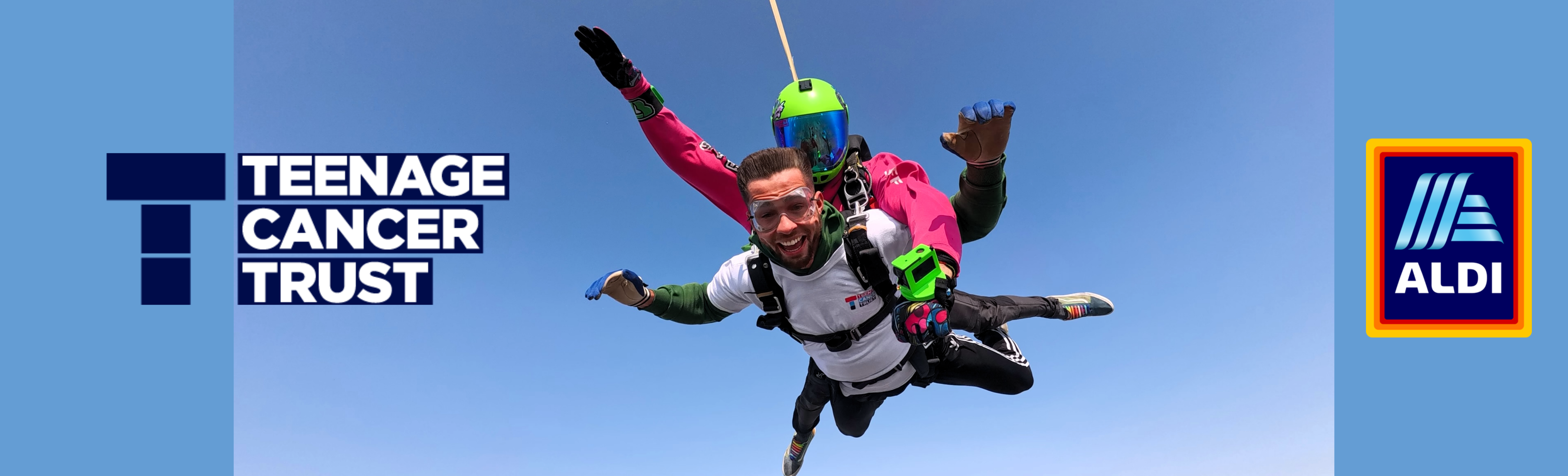 Skydiver in tandem freefall against a clear blue sky, promoting Teenage Cancer Trust with Aldi branding.