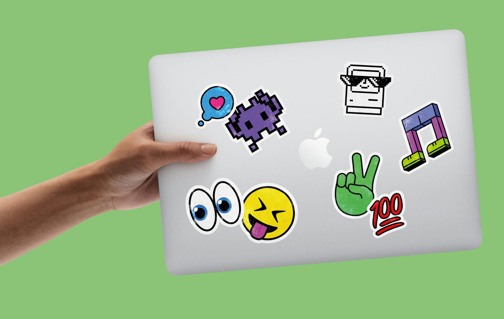 Hand holding MacBook with stickers