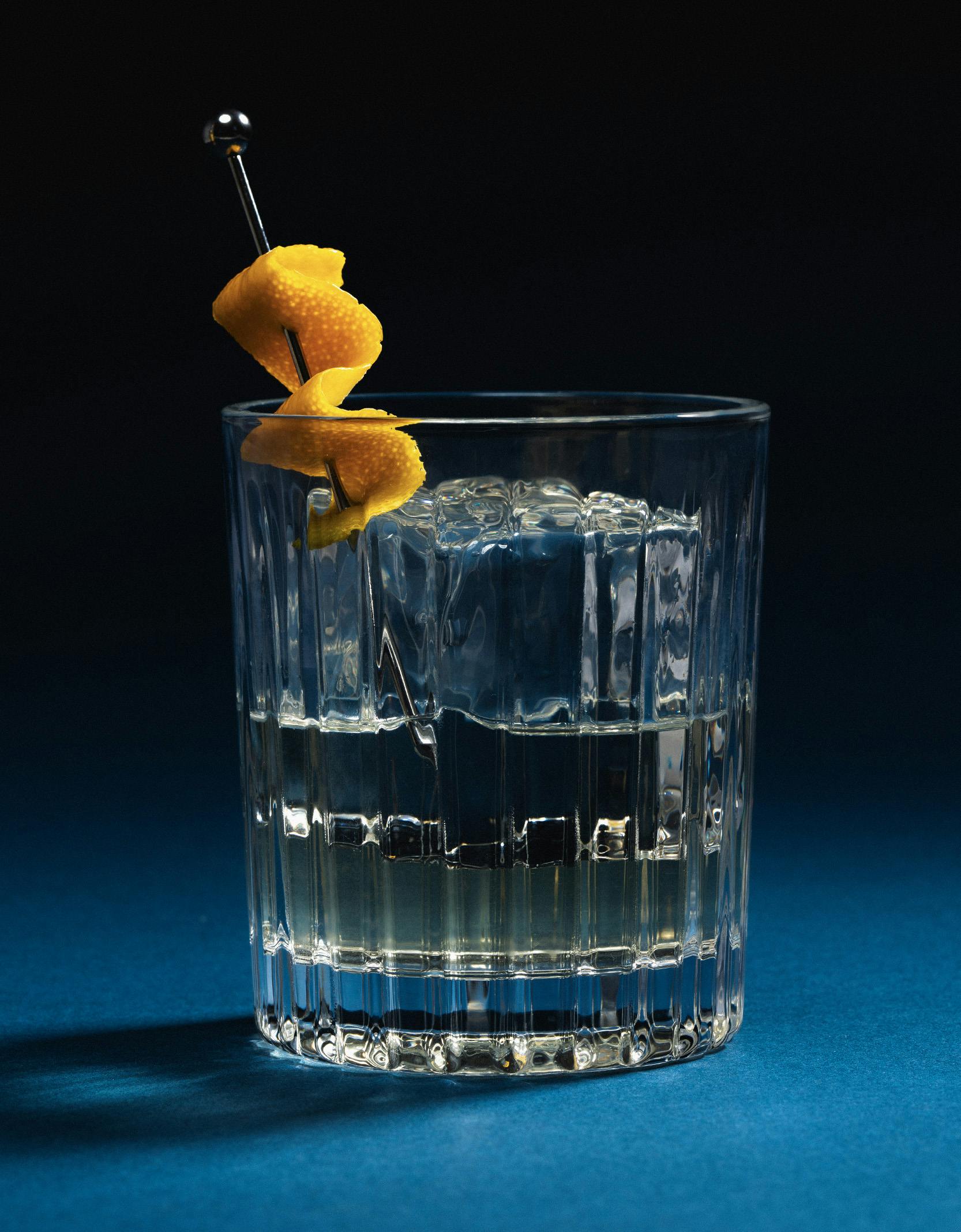 Cocktail glass with orange garnish on blue-black background