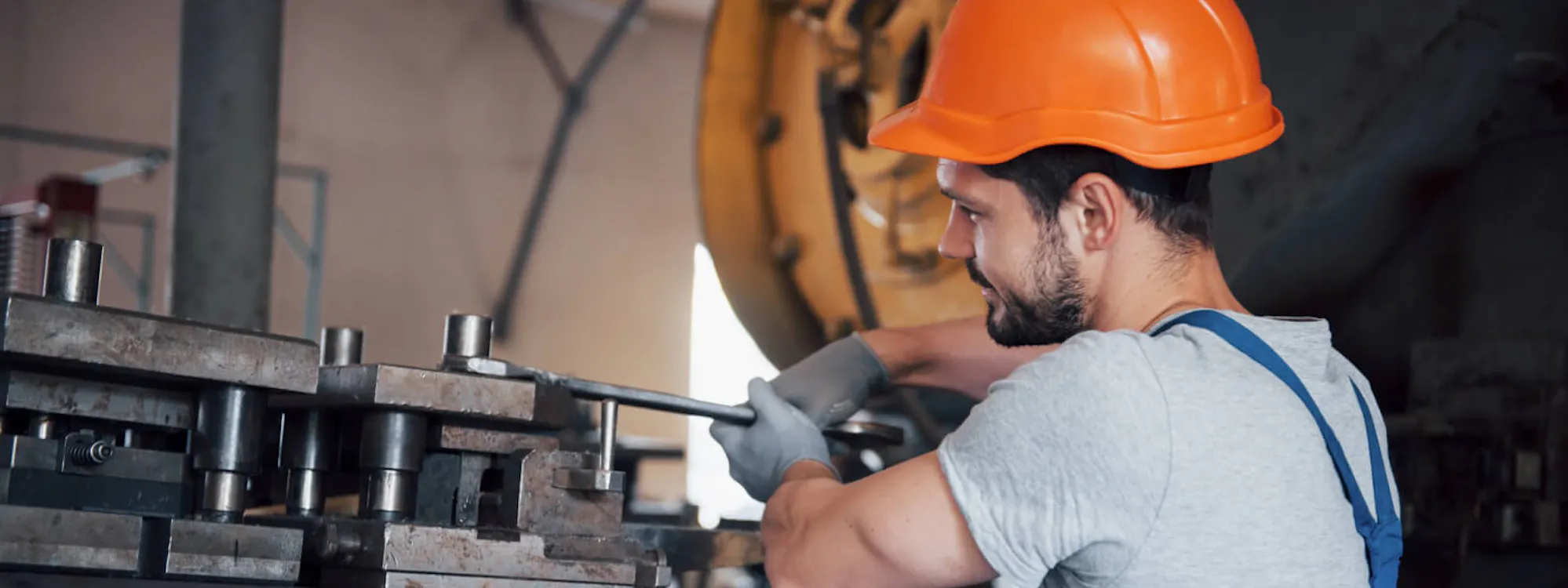 Monteur bei der mechanischen Montage: Werkzeugeinbau an einer Presse mit Schutzhelm und Handschuhen