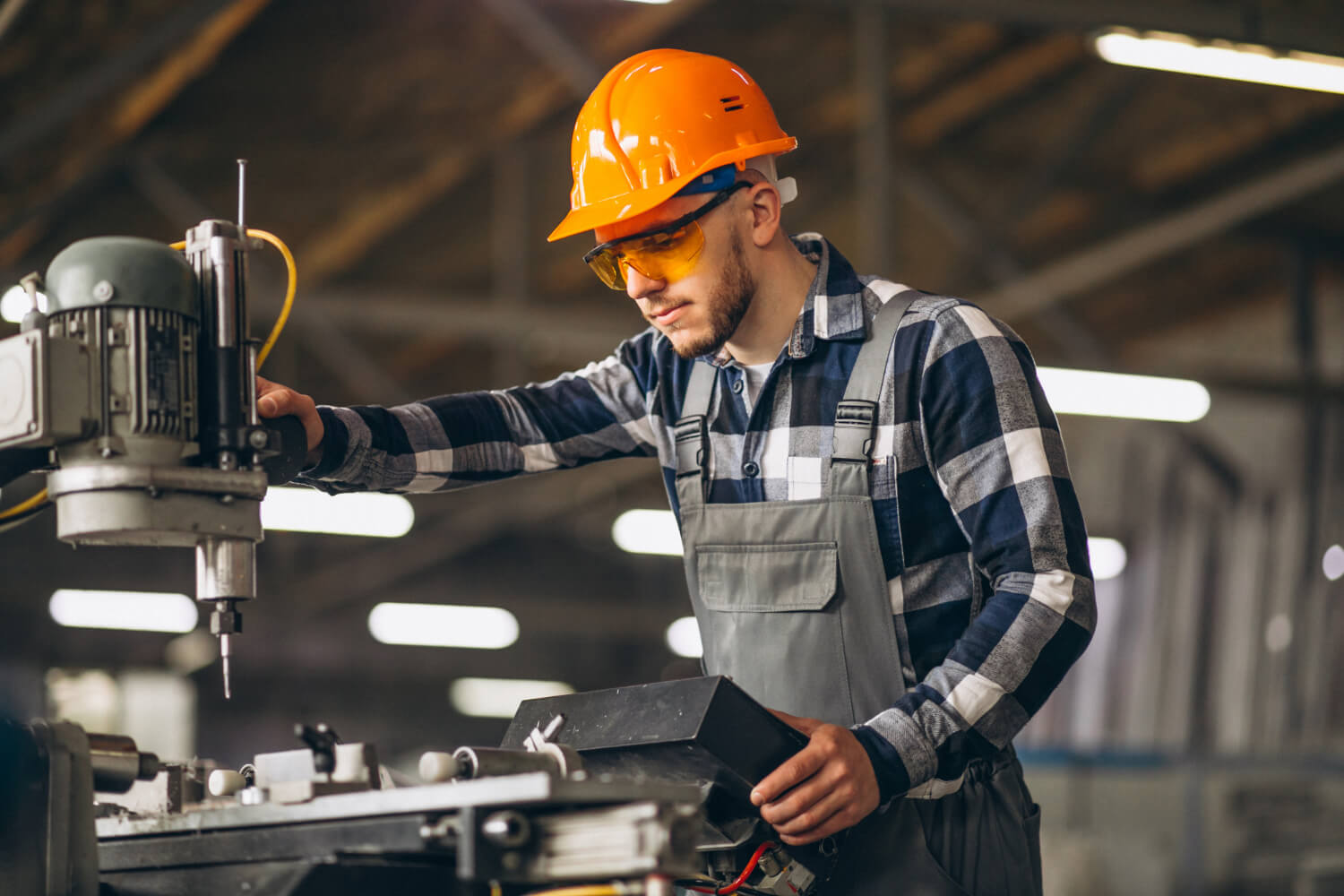 Industriemonteur mit Schutzhelm und Schutzbrille bei der Maschinenmontage an einer Werkzeugmaschine