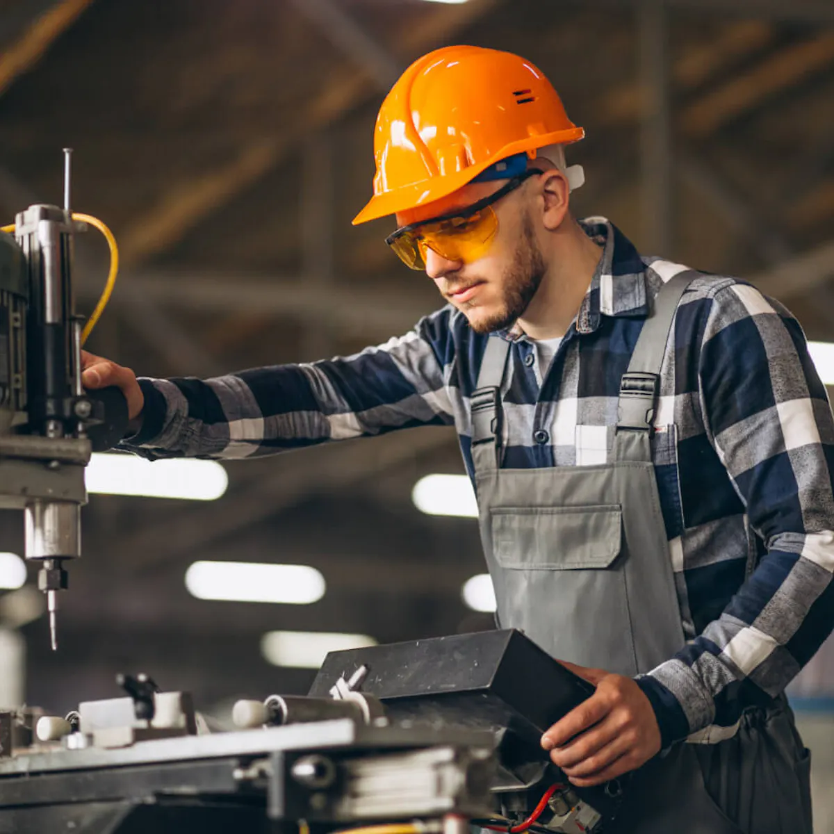 Industriemonteur mit Schutzhelm und Schutzbrille bei der Maschinenmontage an einer Werkzeugmaschine