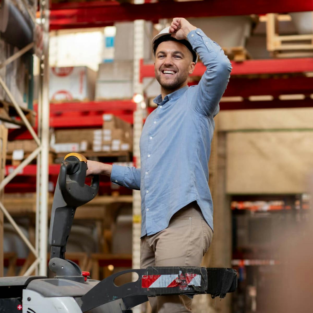 Mitarbeiter in moderner Lagerhalle mit Palettenhubwagen – lächelnd und motiviert bei der Arbeit. Intralogistik Anbieter für effiziente Lager- und Transportprozesse.