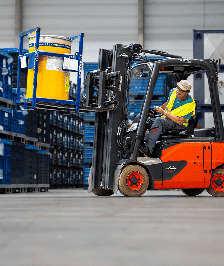 Mann fährt Stapler und transportiert Fässer