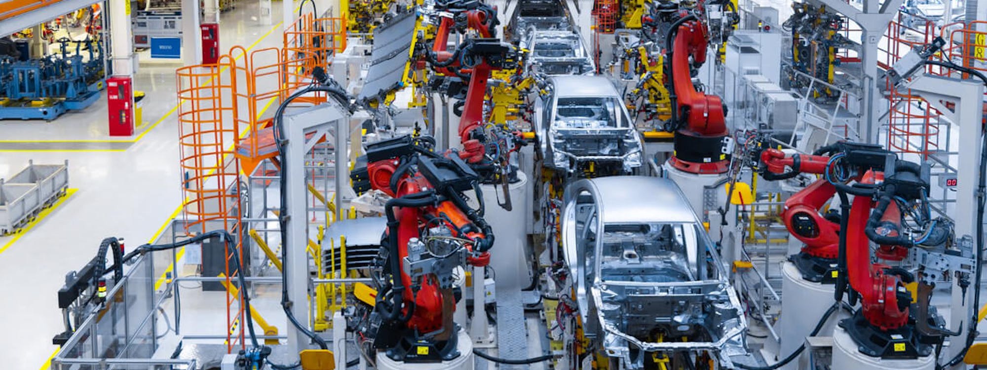 Automatisierte Fahrzeugproduktion mit Industrierobotern: Blick auf eine moderne Fertigungsstraße in der Automobilindustrie, auf der Karosserien taktgenau verarbeitet werden.