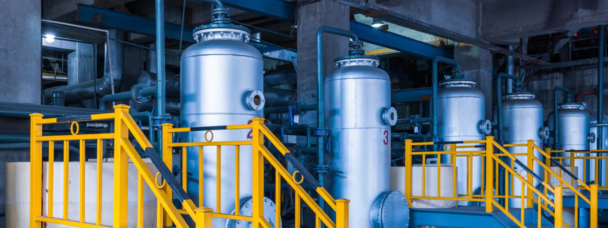 Industrielle Druckbehälter in einer Chemieanlage mit gelben Sicherheitstreppen und Geländern – typische Bereiche, in denen vor Befahren eine professionelle Freimessung nach DGUV erforderlich ist.
