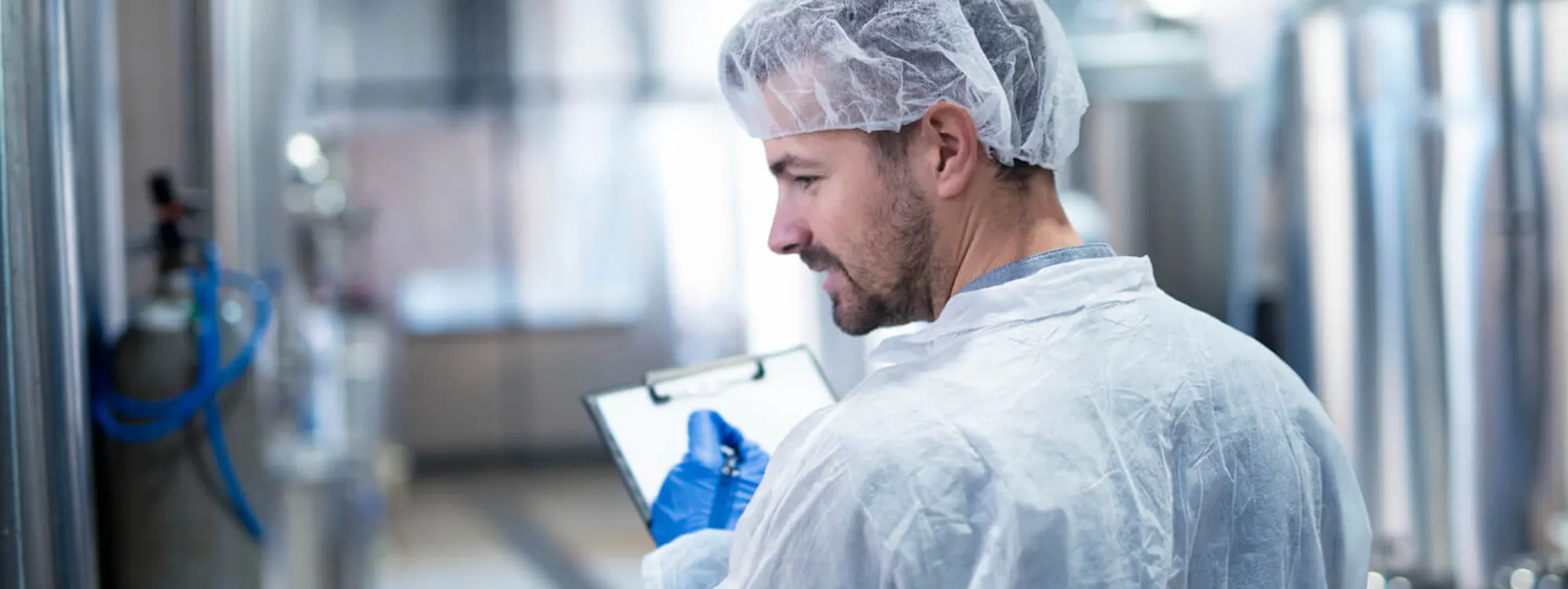 Qualitätskontrolle in der Reinraumproduktion – Mitarbeiter dokumentiert Prozesse nach GMP und Hygienevorgaben
