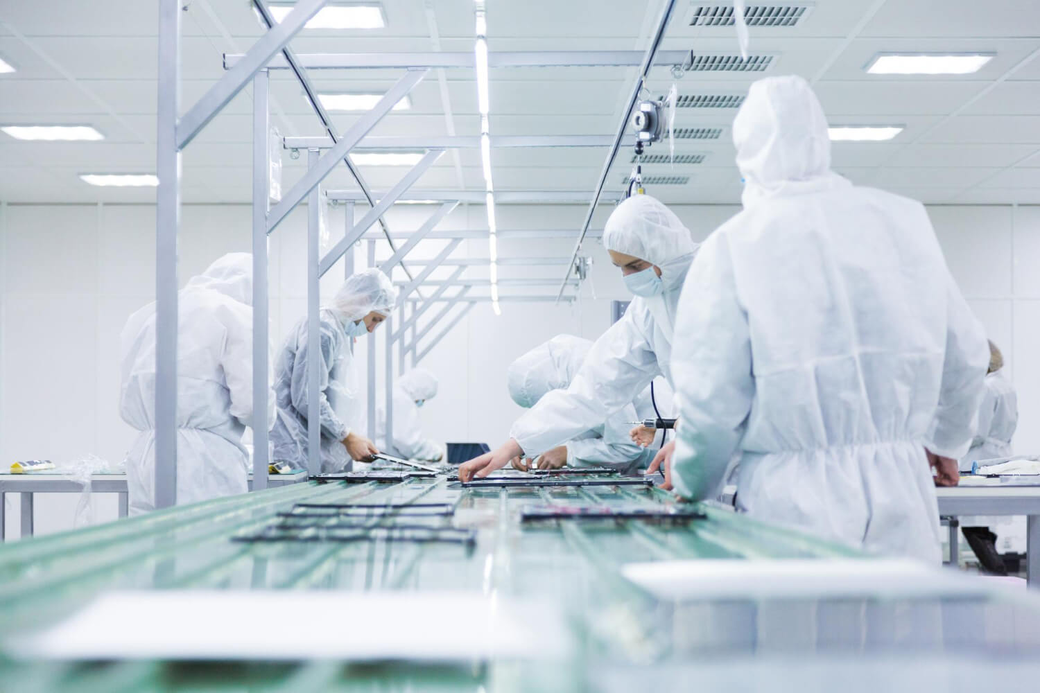Mitarbeitende in Reinraumkleidung bei der Reinraumproduktion und Montage elektronischer Bauteile