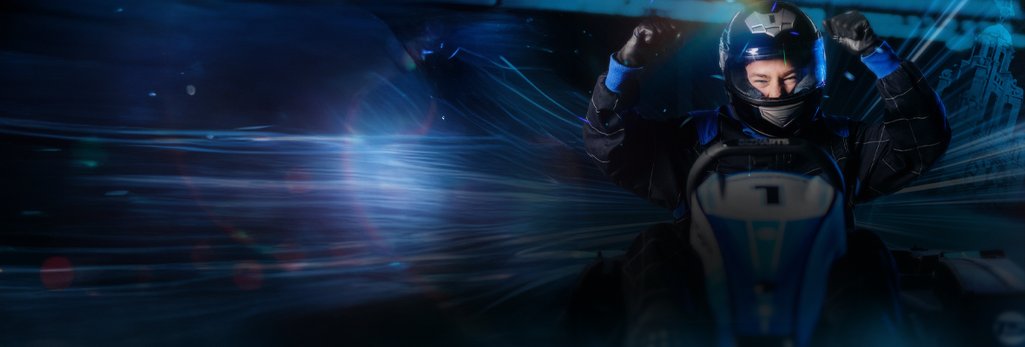 Man sitting in a Go Kart smiling with arms in the air