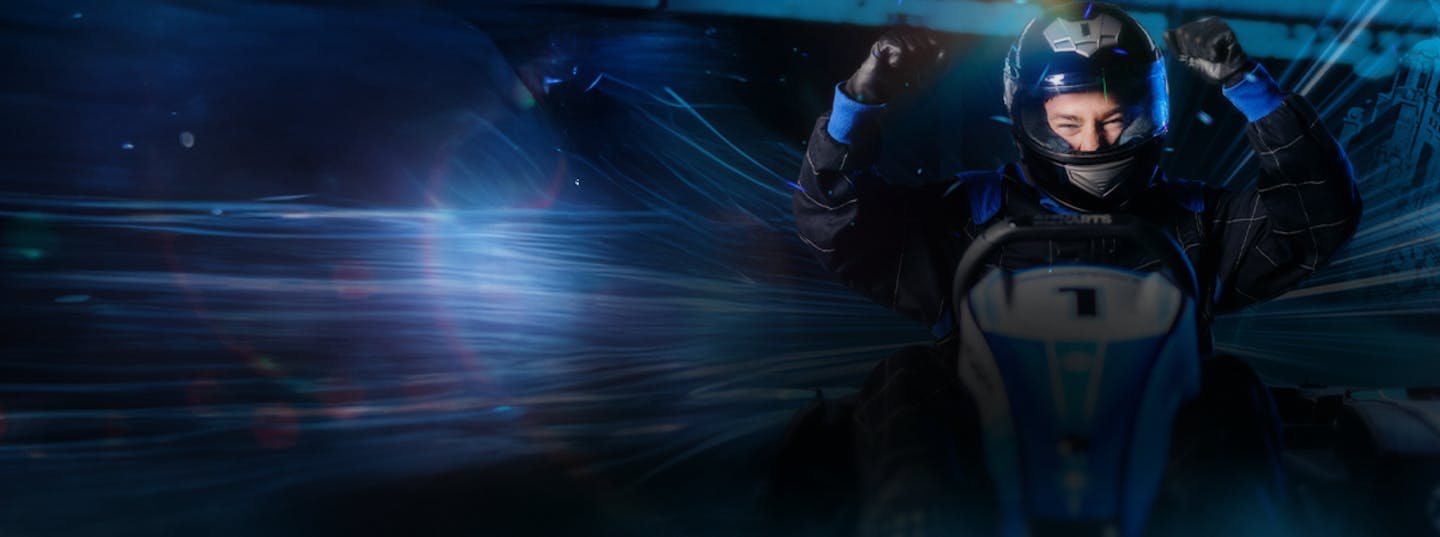 Man sitting in a Go Kart smiling with arms in the air