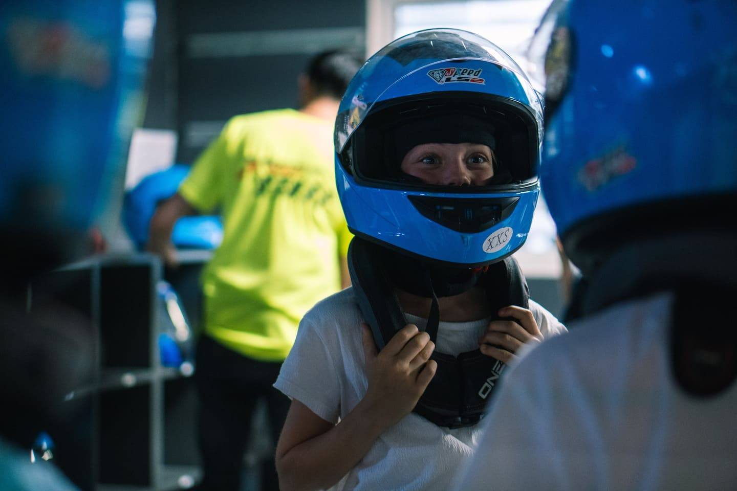 Zwei Kinder mit Helmen stehen in der Boxengasse und freuen sich auf das bevorstehende Rennen