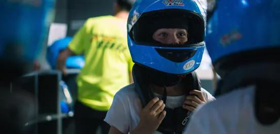 Zwei Kinder mit Helmen stehen in der Boxengasse und freuen sich auf das bevorstehende Rennen