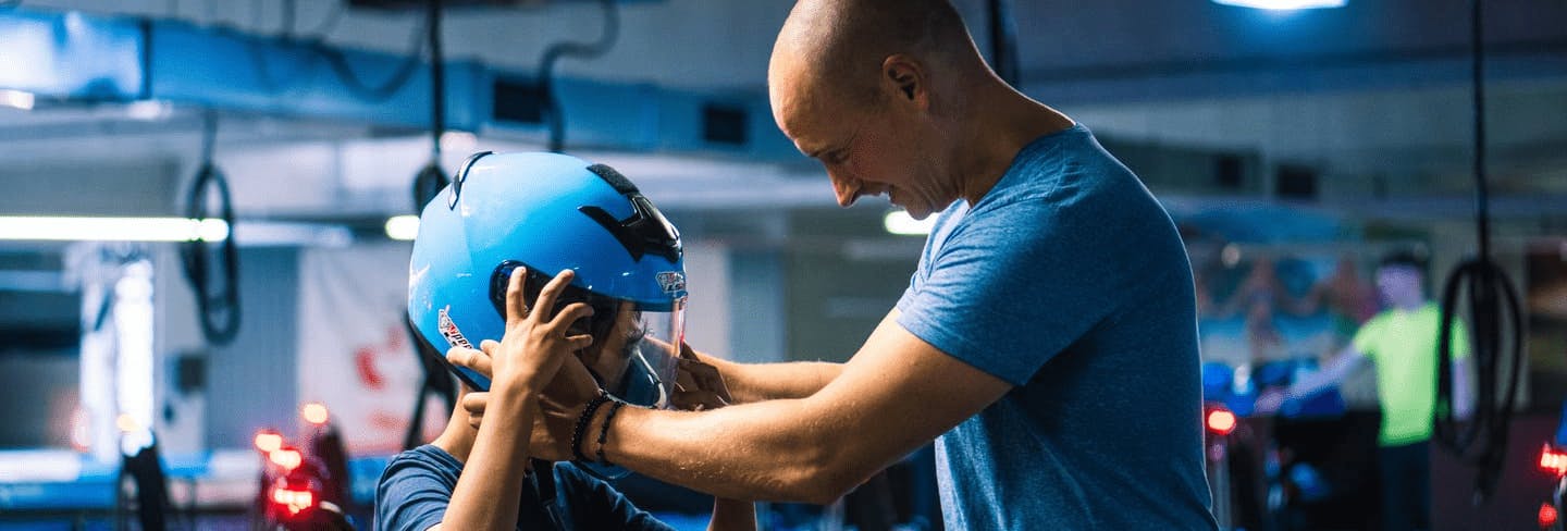 Ein Vater setzt seinem Kind den Helm vor dem Rennen auf