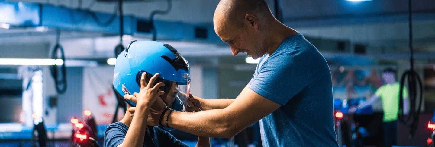 Ein Vater setzt seinem Kind den Helm vor dem Rennen auf