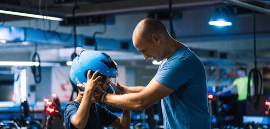 Ein Vater setzt seinem Kind den Helm vor dem Rennen auf
