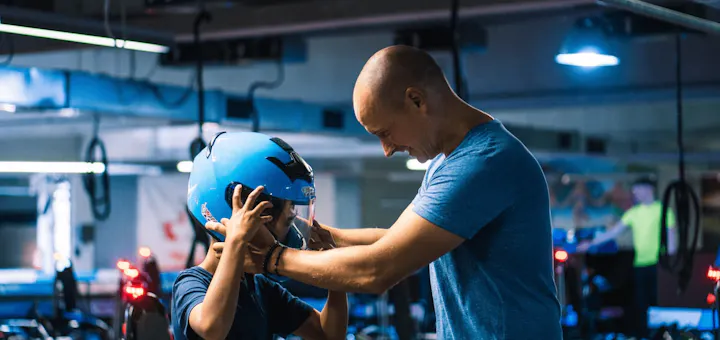 Ein Vater setzt seinem Kind den Helm vor dem Rennen auf