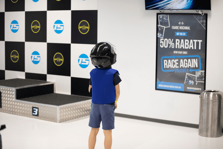 Kind mit Helm, dass vor einem Siegerpodest steht