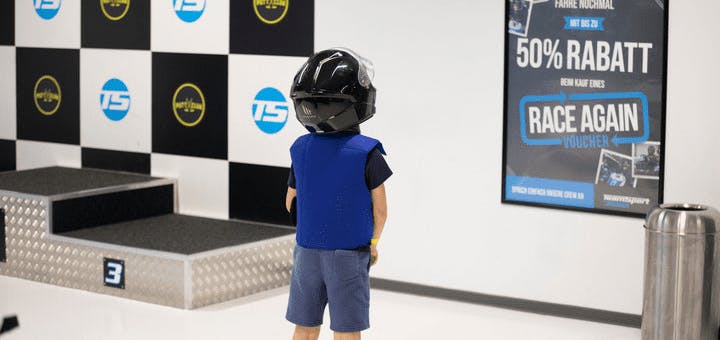 Kind mit Helm, dass vor einem Siegerpodest steht