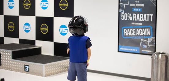 Kind mit Helm, dass vor dem Siegerpodest steht. 