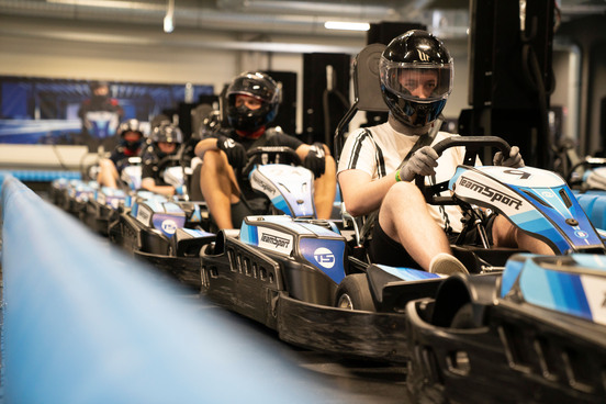 Eine Gruppe von Fahrern sitzt in den E-Karts in der Boxengasse und wartet auf den Rennstart