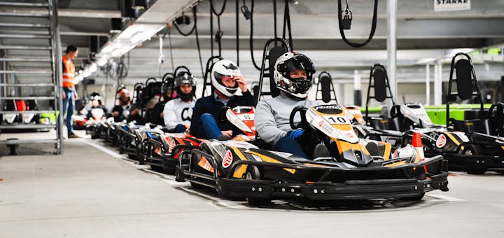 Mehrere Kartfahrer sitzen in ihren Karts in der Boxengasse und warten auf den Start des Rennens