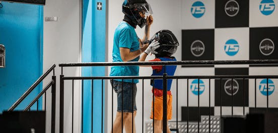 Ein Vater mit Sohn stehen mit angezogenen Helmen vor einem Siegerpodest