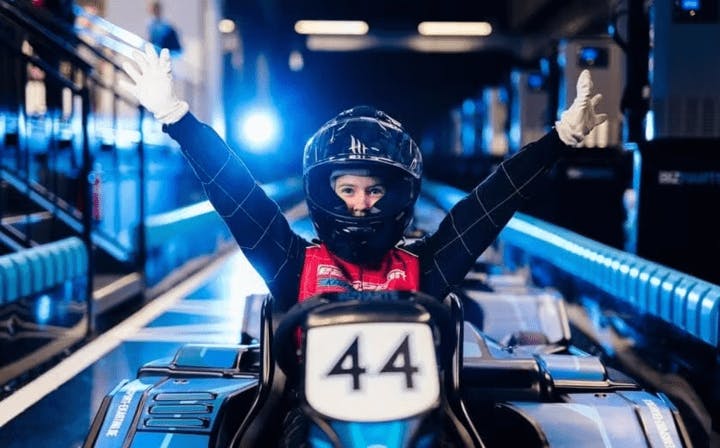 Kid smiling in Electric kart pit lane with arms in the air