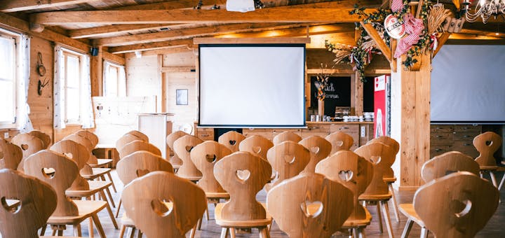 Aufgebaute Sitzreihen vor einer Leinwand im Eventstadl