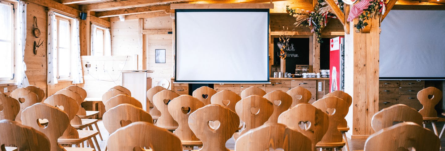 Aufgebaute Sitzreihen vor einer Leinwand im Eventstadl