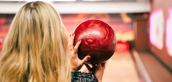 Eine Frau hält eine Bowlingkugel in der Hand