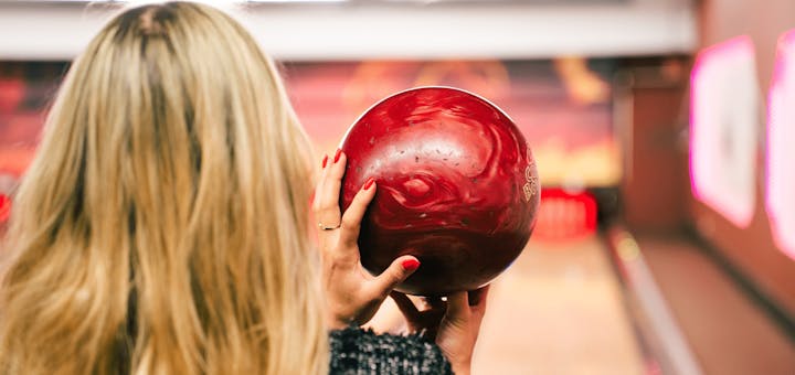 Eine Frau hält eine Bowlingkugel in der Hand