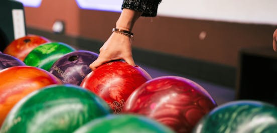 Eine Frau greift nach einer Bowlingkugel