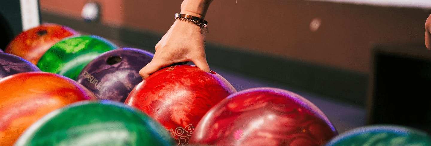 Eine Frau greift nach einer Bowlingkugel