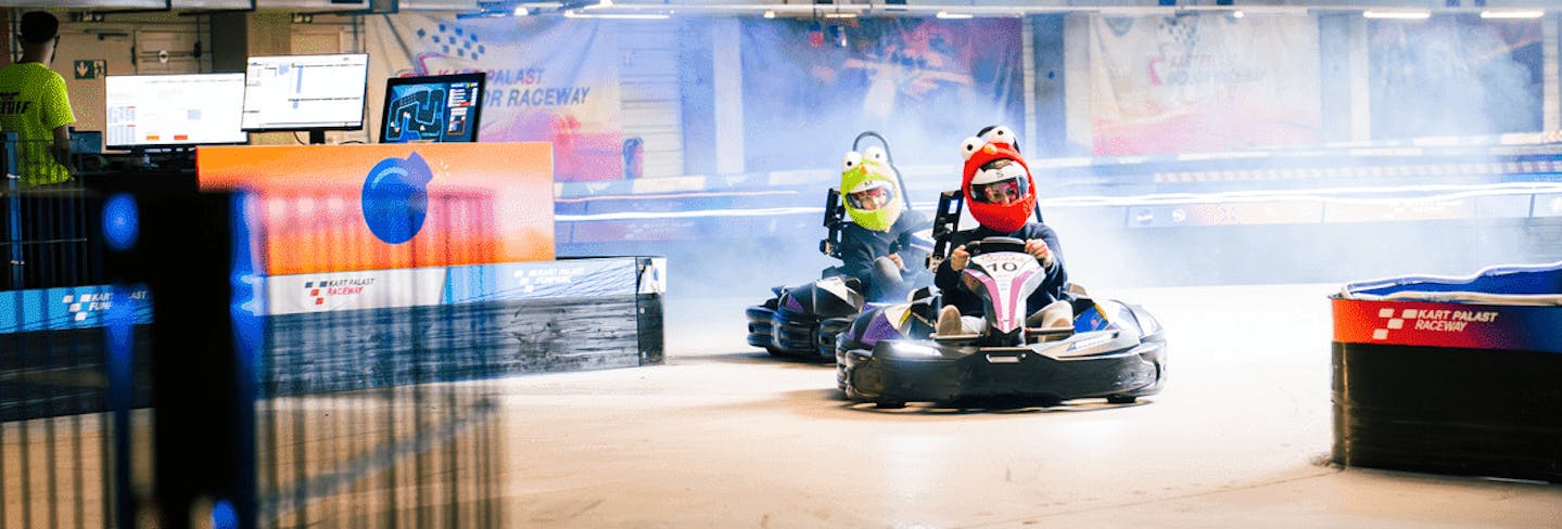 2 Kartfahrer fahren auf der Combat Kart Strecke und tragen Plüsch - Helm - Cover