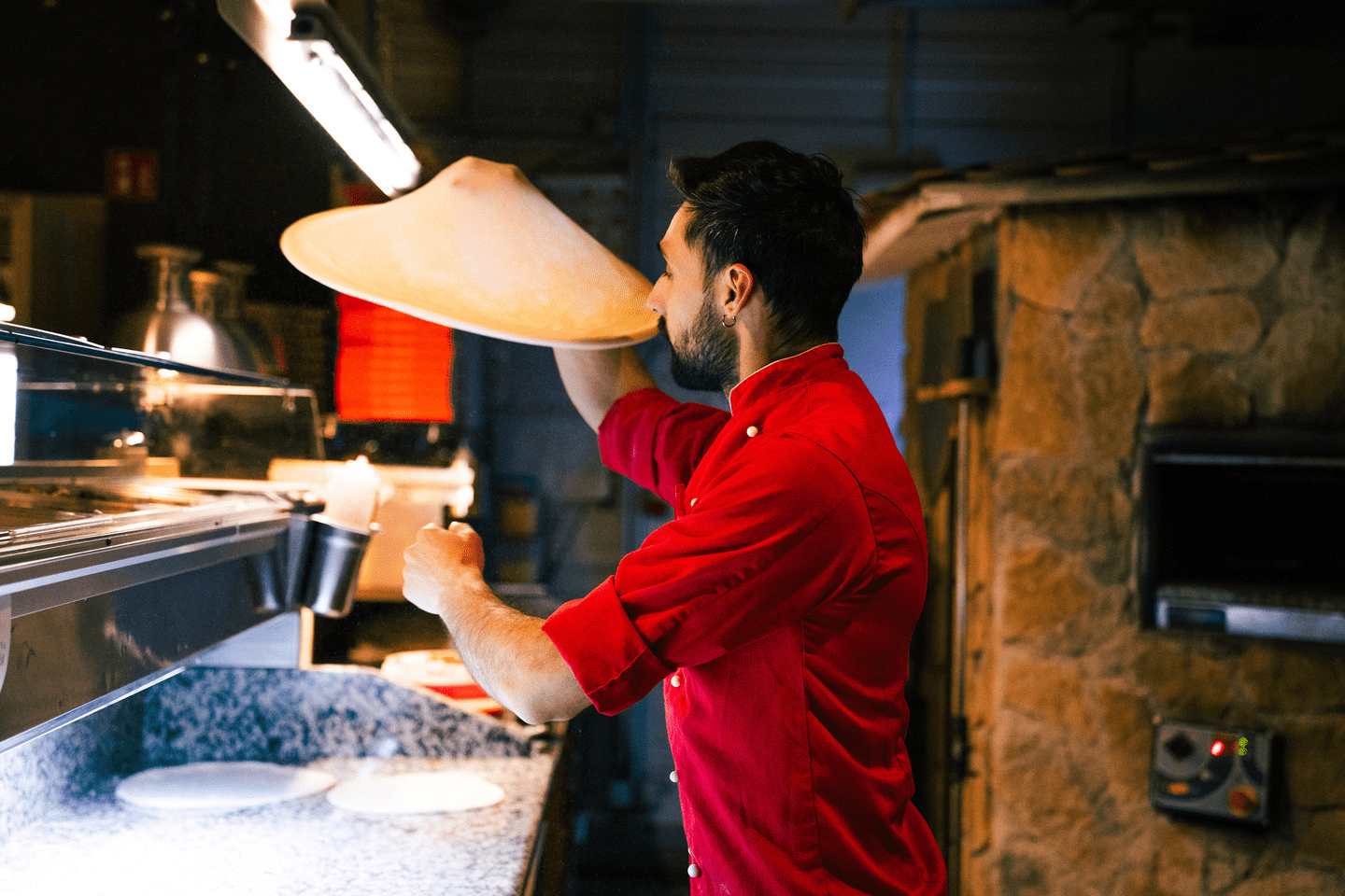 Ein Pizzabäcker schwingt einen Pizzateig durch due Luft 