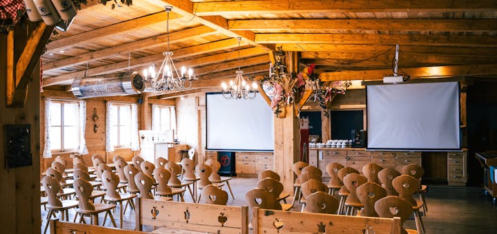 Das Eventstadl mit aufgebauten Sitzreihen und 2 Bildschirmen bereit für die nächste Veranstaltung